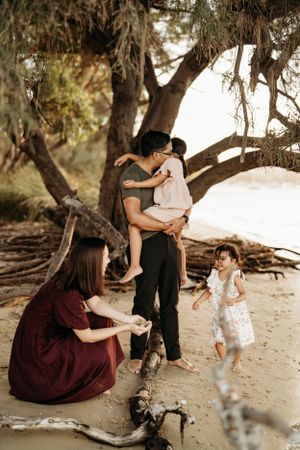 Family spending quality time together under shady trees at beach setting.
