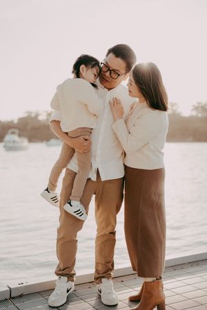 Intimate family moment captured on a wooden deck during golden hour with soft lighting.