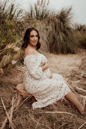 White floral dress against tall pampas grass in a dreamy outdoor photoshoot with warm natural lighting.