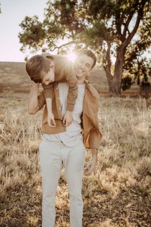 Playful piggyback ride between two people in golden sunlit field.