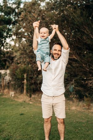 Joyful outdoor playtime with lifting and spinning motions on green grass.
