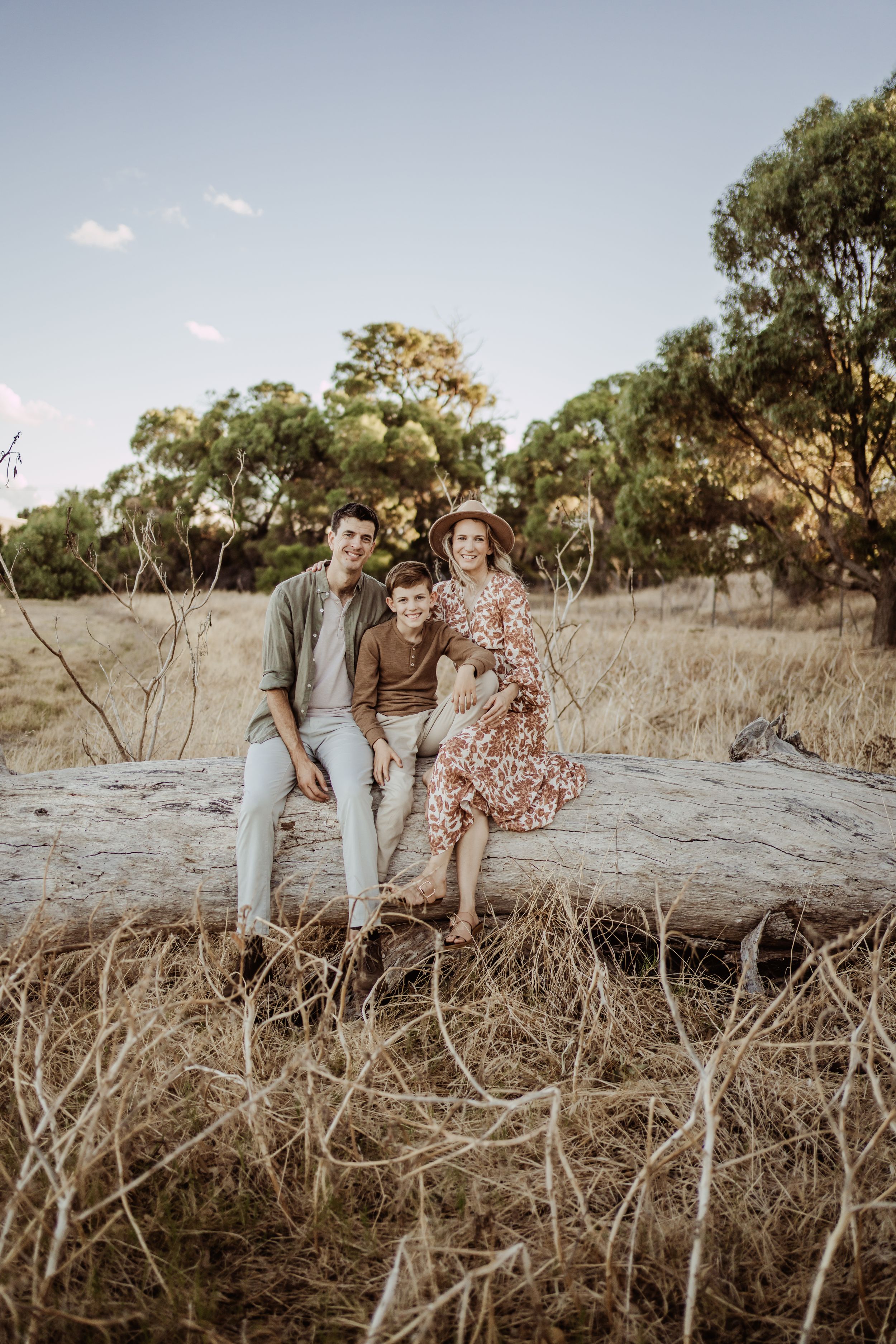 Group relaxing on fallen tree trunk in rustic outdoor setting during golden hour.