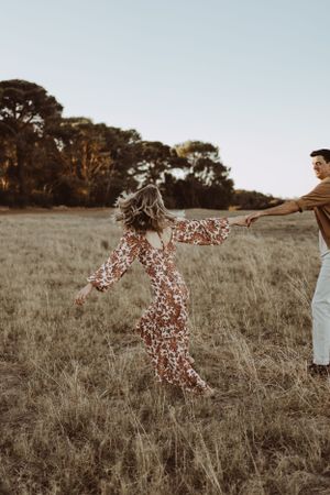 Playful interactions in a golden field during sunset with people running and having fun.