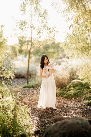Young child playing in a serene outdoor setting with soft sunlight filtering through trees.