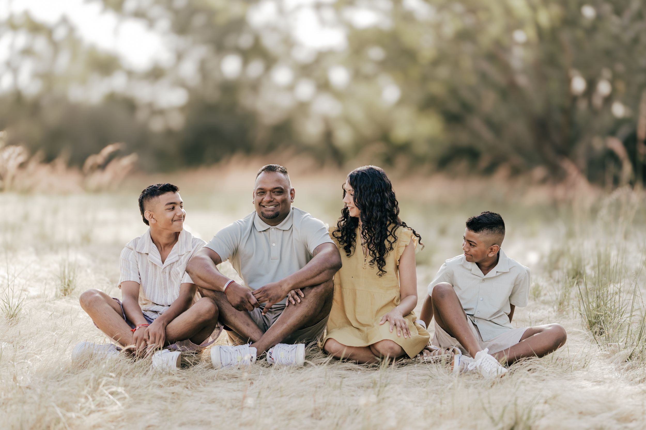 Happy couple sharing playful moments outdoors in a field during golden hour.