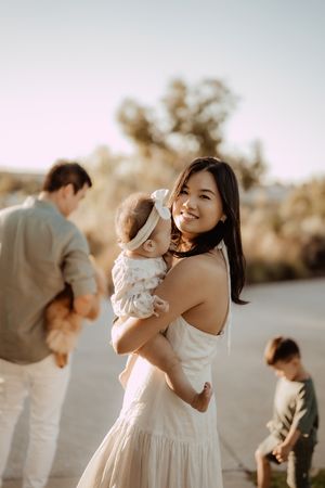 A warm outdoor family portrait showing people embracing and smiling in natural lighting at sunset.
