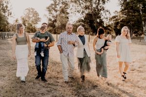 A group of people walking together in casual attire through a golden field at sunset.