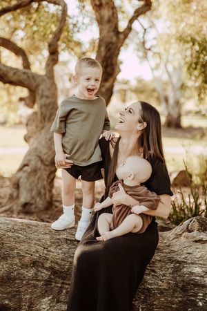 Candid family photo series showing joyful, playful moments on a fallen tree trunk in a sunny outdoor setting.
