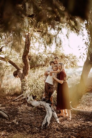 Romantic outdoor photo session under a large willow tree during golden hour in a natural setting.