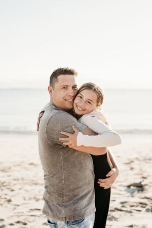 A touching moment shared between two people hugging on a sunny beach.