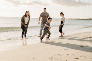 Beautiful beach scene at sunset with people walking along the sandy shoreline.