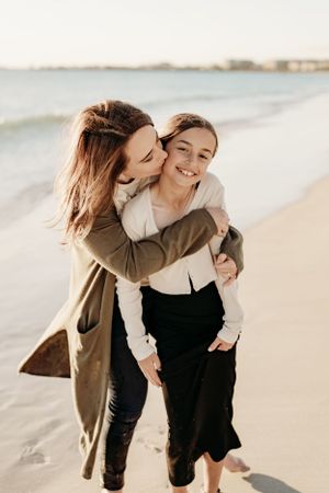 Intimate family moment captured between parent and child walking together on a sunny beach.