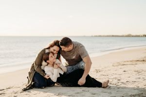 A tender family moment shared on a sandy beach at sunset.