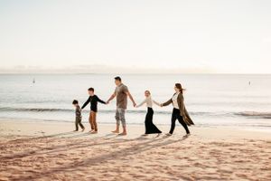 Silhouettes of people playing and walking along a beach at sunset.