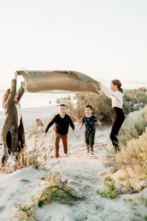 Group having fun jumping and playing together on sand dunes at sunset.