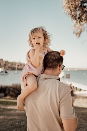 Sweet outdoor moment between parent and child sharing cuddles and giggles on a sunny afternoon by the water.