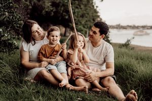 A series of candid outdoor family photos taken on a grassy hill during golden hour shows intimate moments of connection.