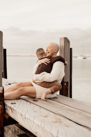 Heartwarming moment of laughter shared on wooden dock by the water.