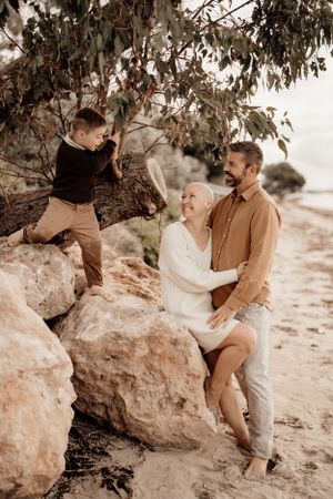 Family enjoying time together on rocky beach with eucalyptus trees.