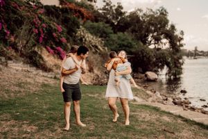 Couple holding babies while enjoying scenic coastal view.