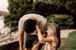 Sweet bonding moment captured between parent and child in a lush outdoor setting.