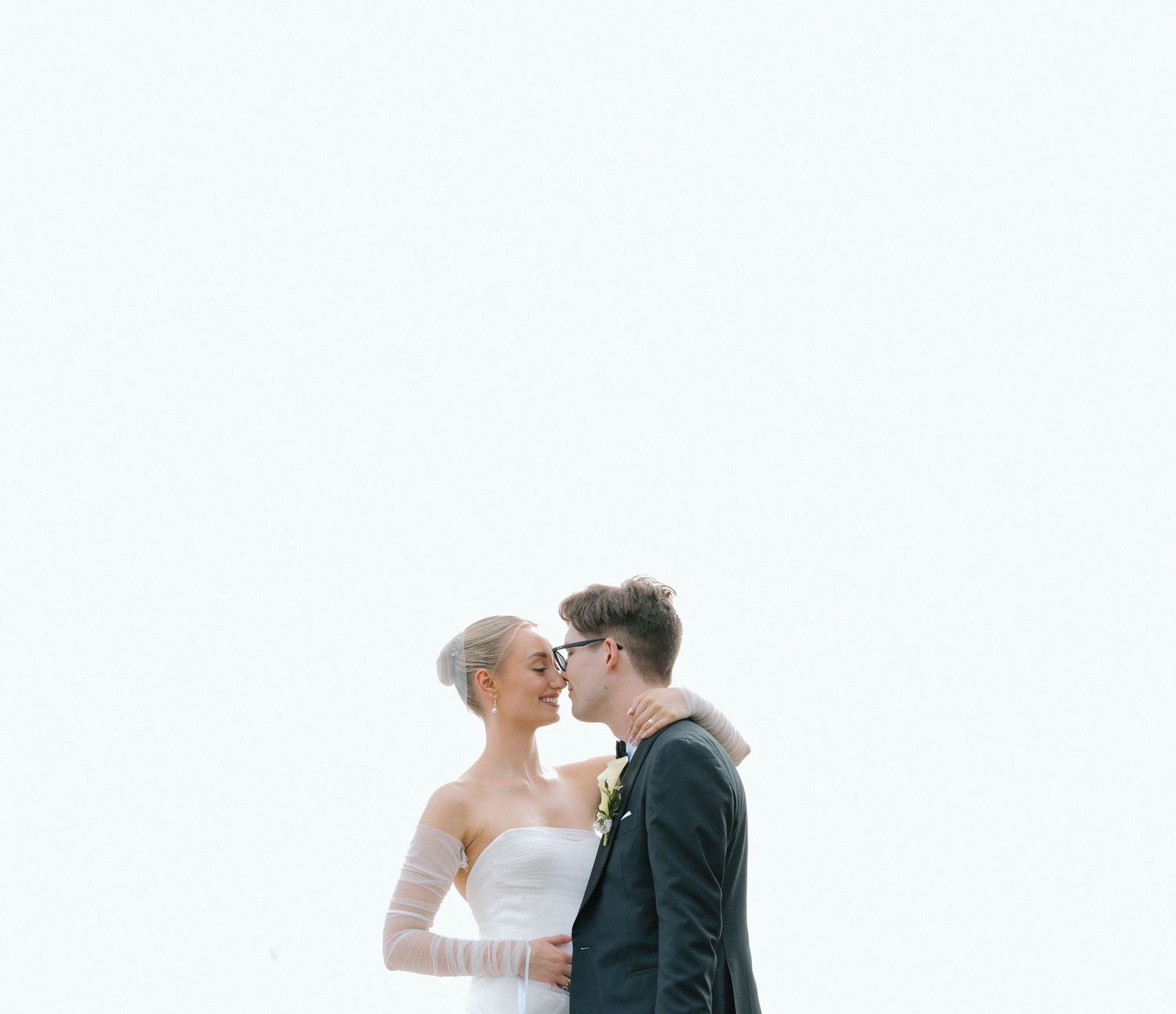 A romantic moment between newlyweds against a bright white background.