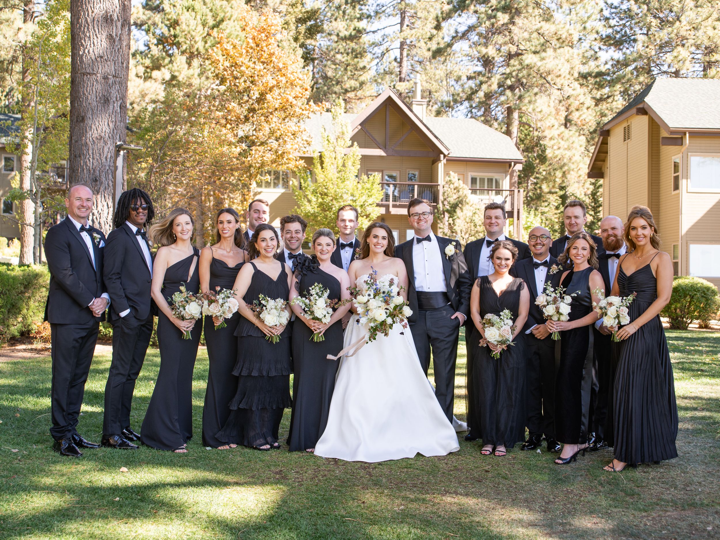 Wedding party stands together on the lawn in formal black attire at Hyatt Regency Lake Tahoe.