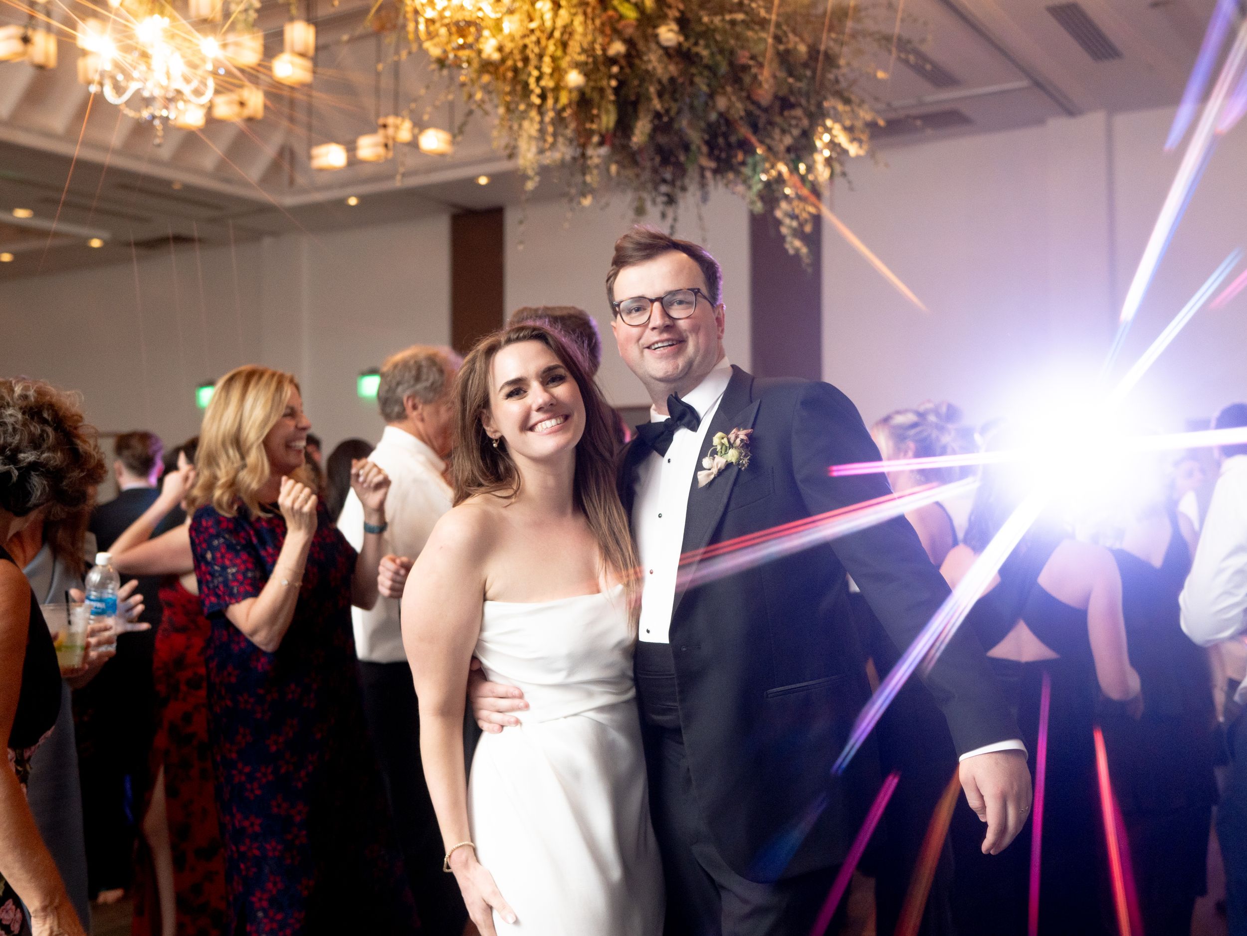 Wedding reception in an elegant ballroom with chandeliers and bright camera flash creating a dramatic lighting effect at lakeside ballroom.