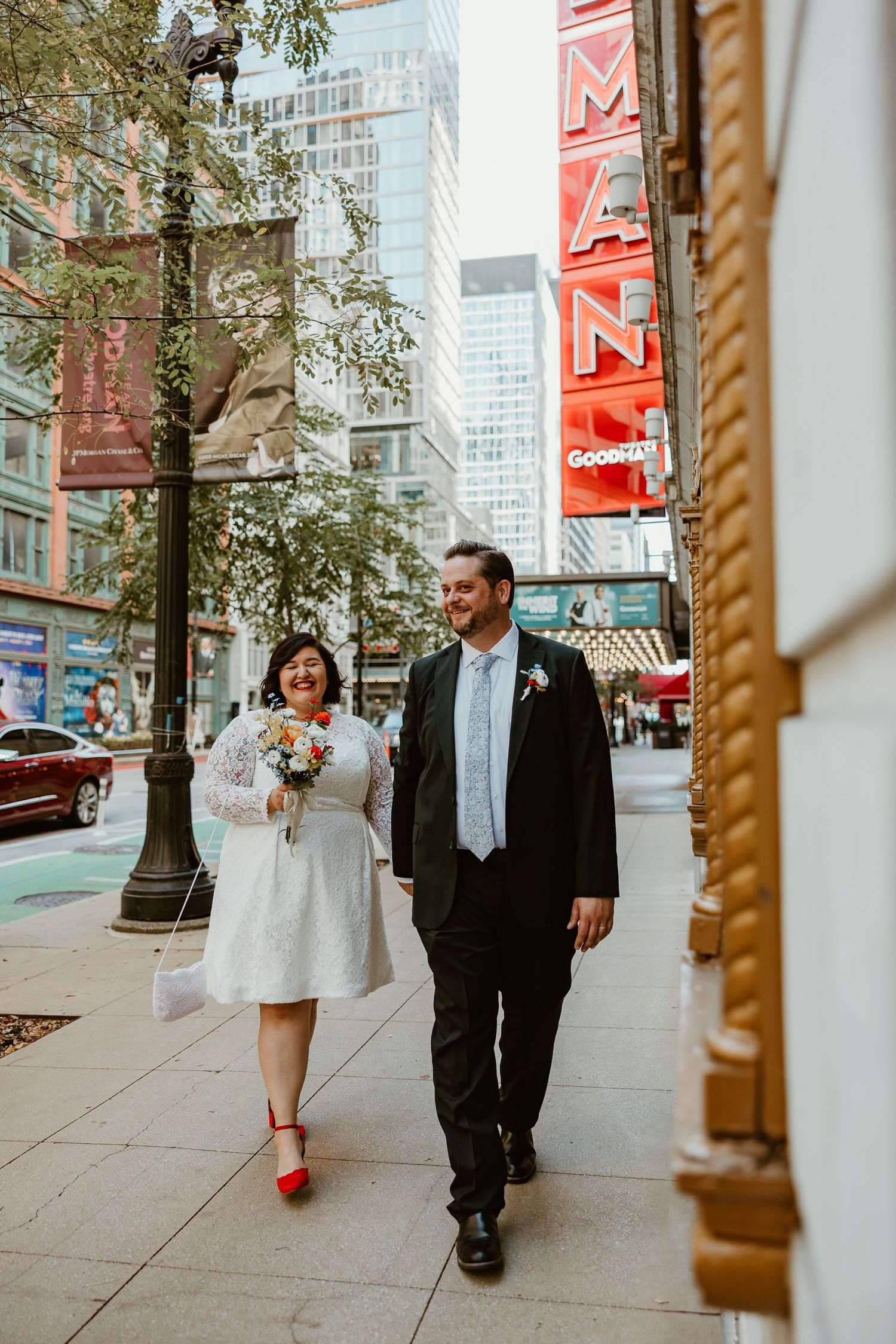 Couple walking down Chicago street past vintage Goodman theater sign.