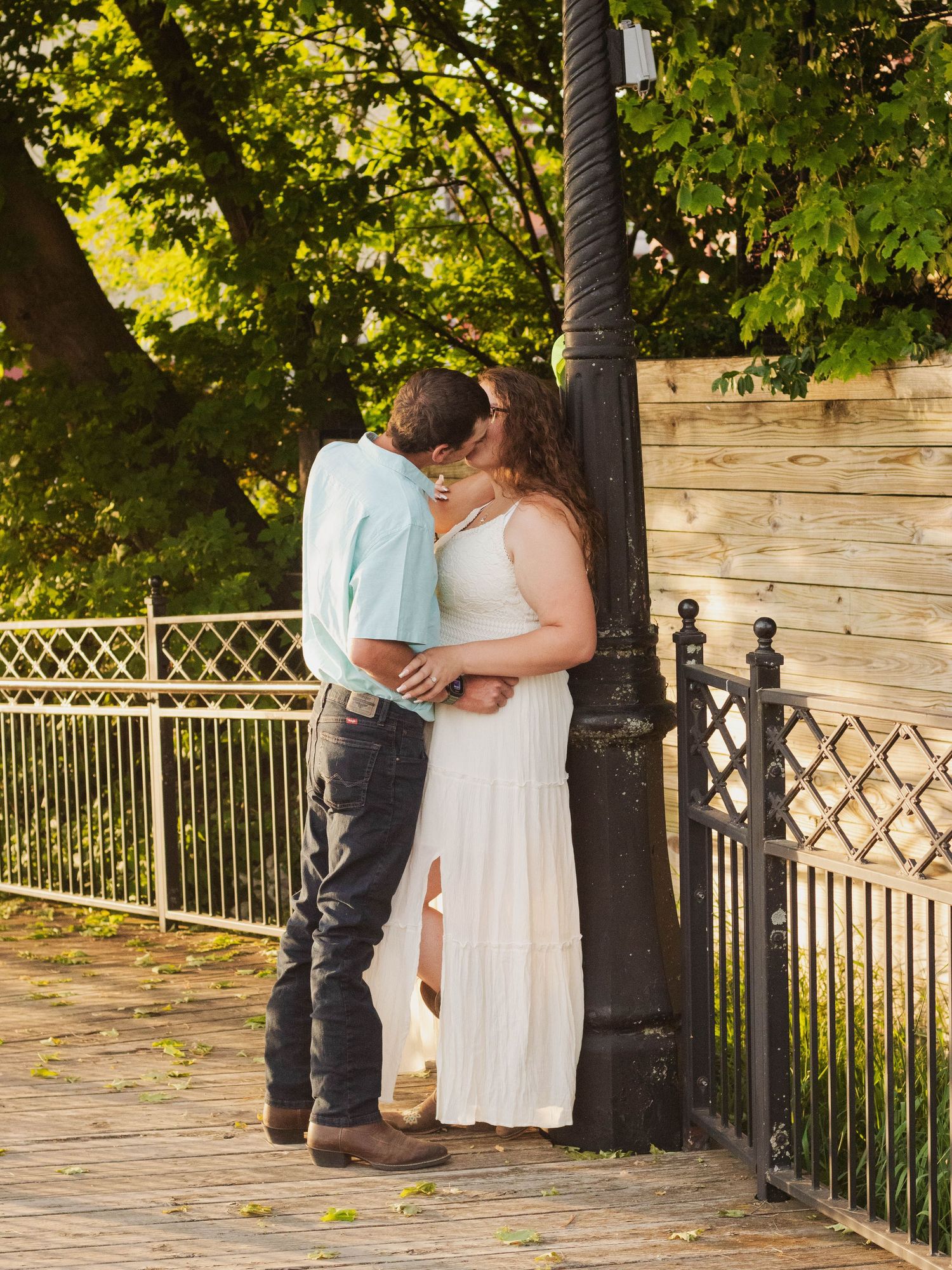 A romantic moment shared between a couple by a decorative lamp post in summer sunlight.