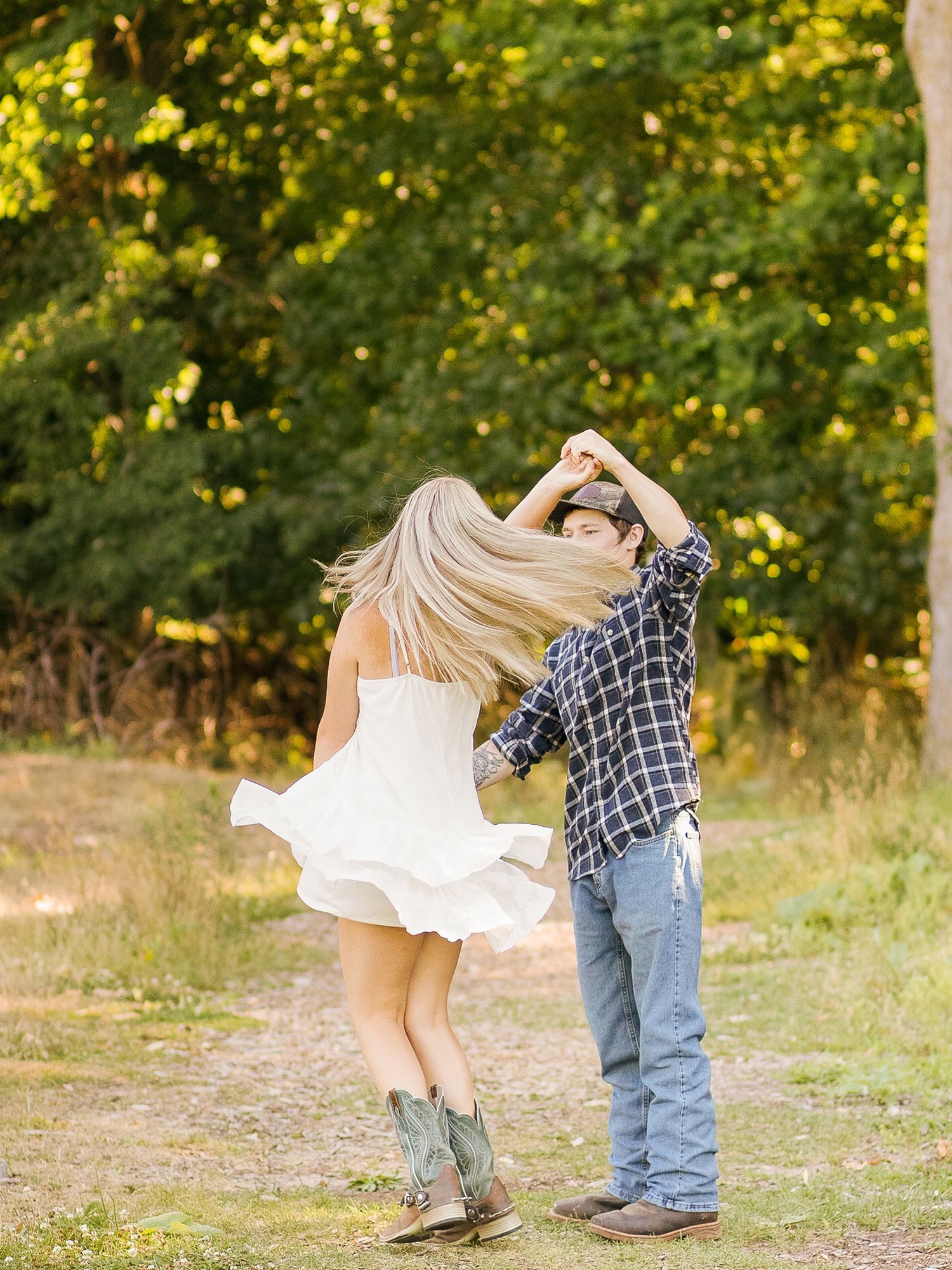 Couple dancing outdoors with person in white dress spinning against autumn foliage background.