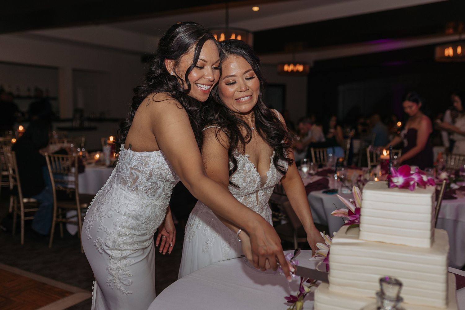 Two brides cut a 2 tier wedding cake in a ballroom at Tom Ham's Lighthouse in San Diego.