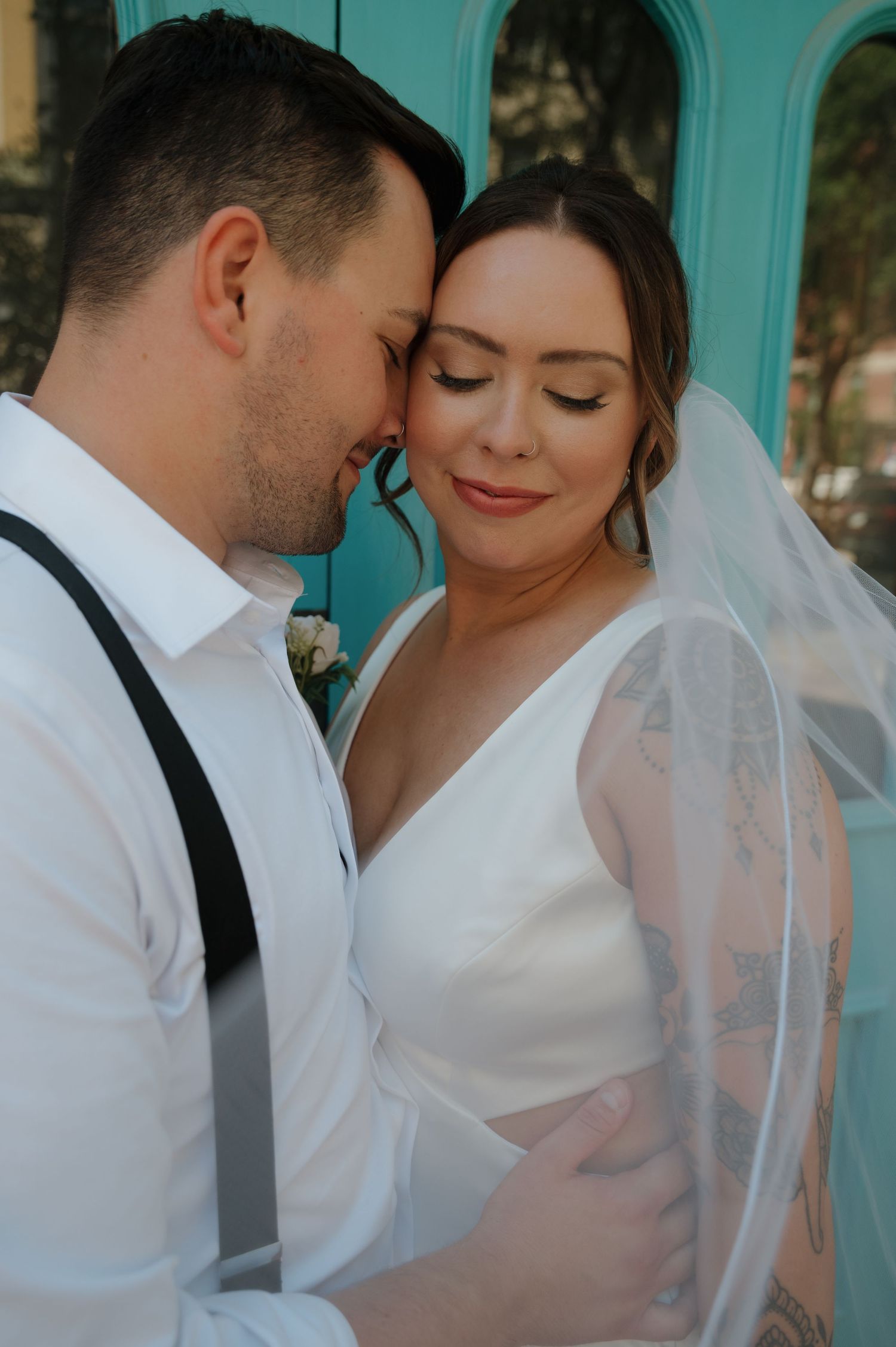 Bride and groom share an intimate moment together in front of a turquoise door.