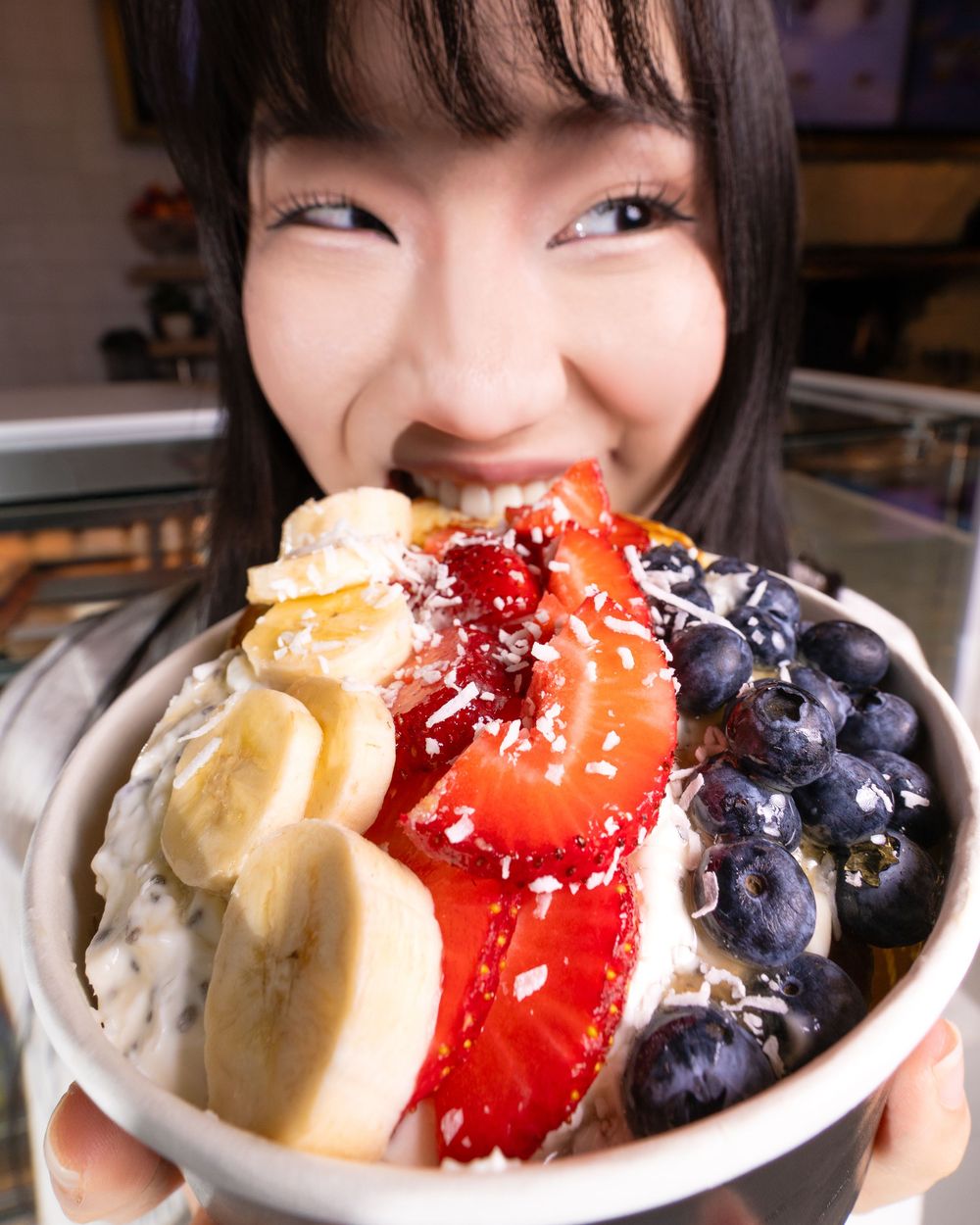 Colorful acai bowl topped with fresh blueberries, strawberries, and sliced bananas in a white bowl.