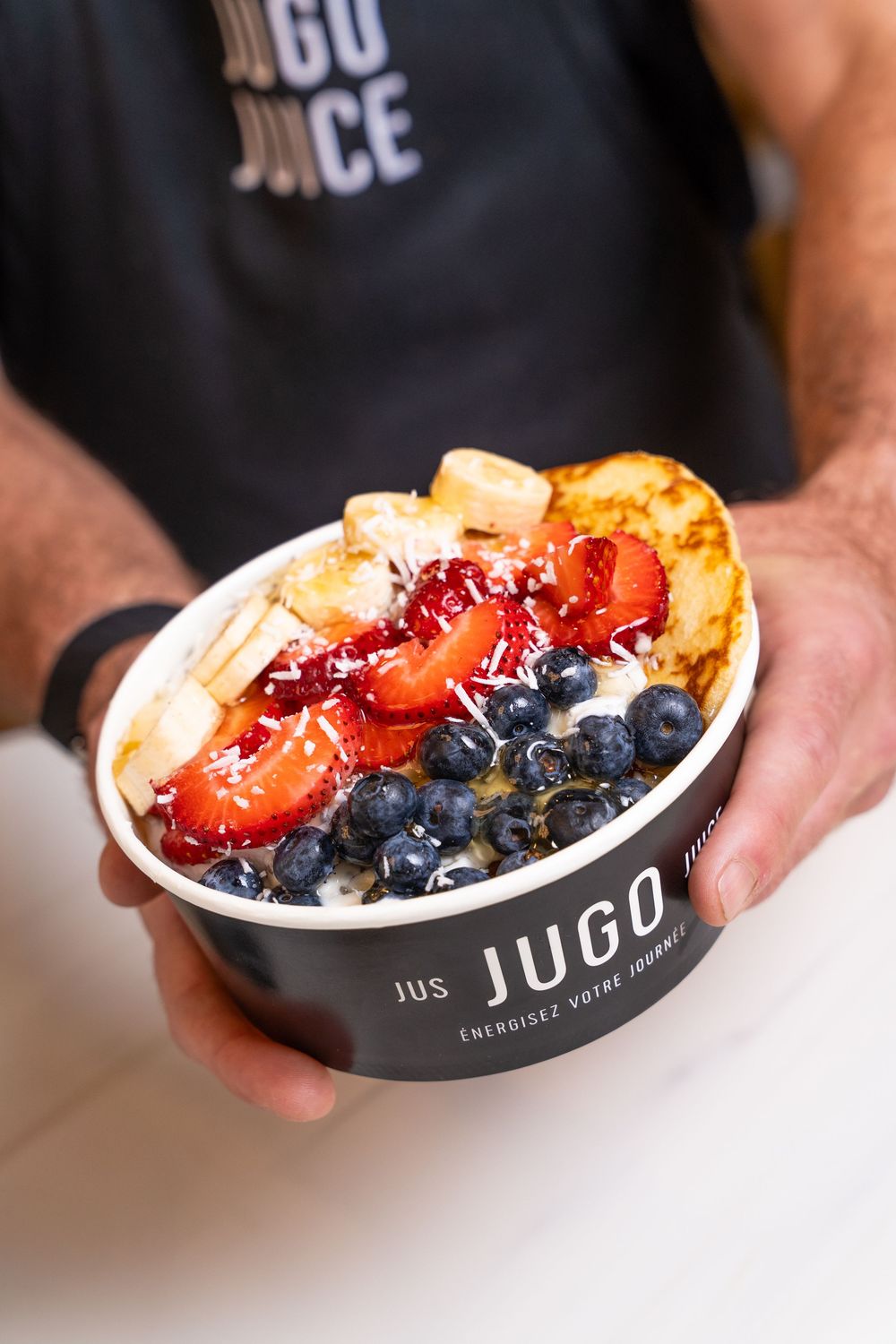 A bowl from Jugo restaurant filled with fresh berries, bananas and other toppings in an acai or smoothie bowl.