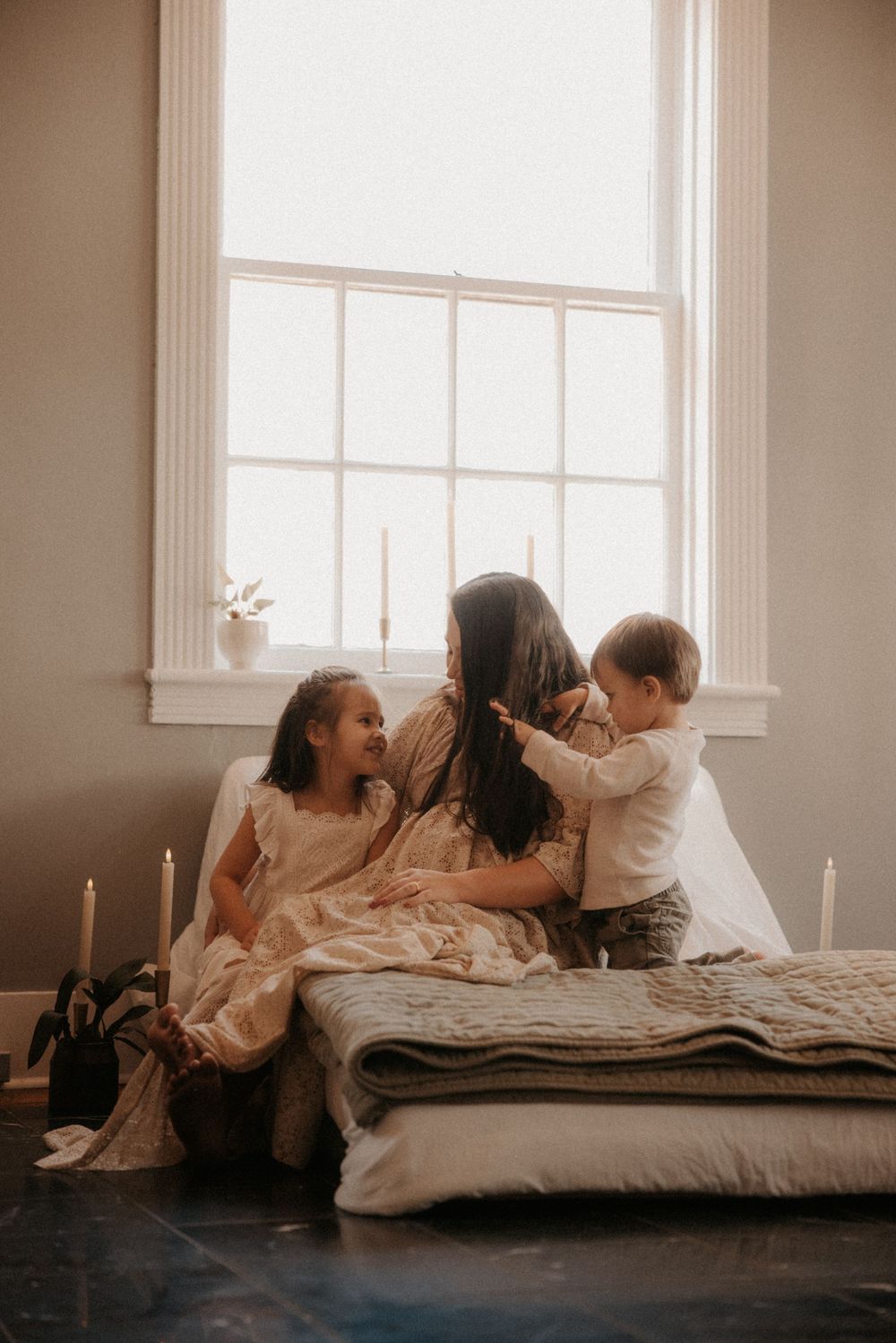 Three warm-toned photos show people relaxing together on a mattress in a sunlit room with white walls.