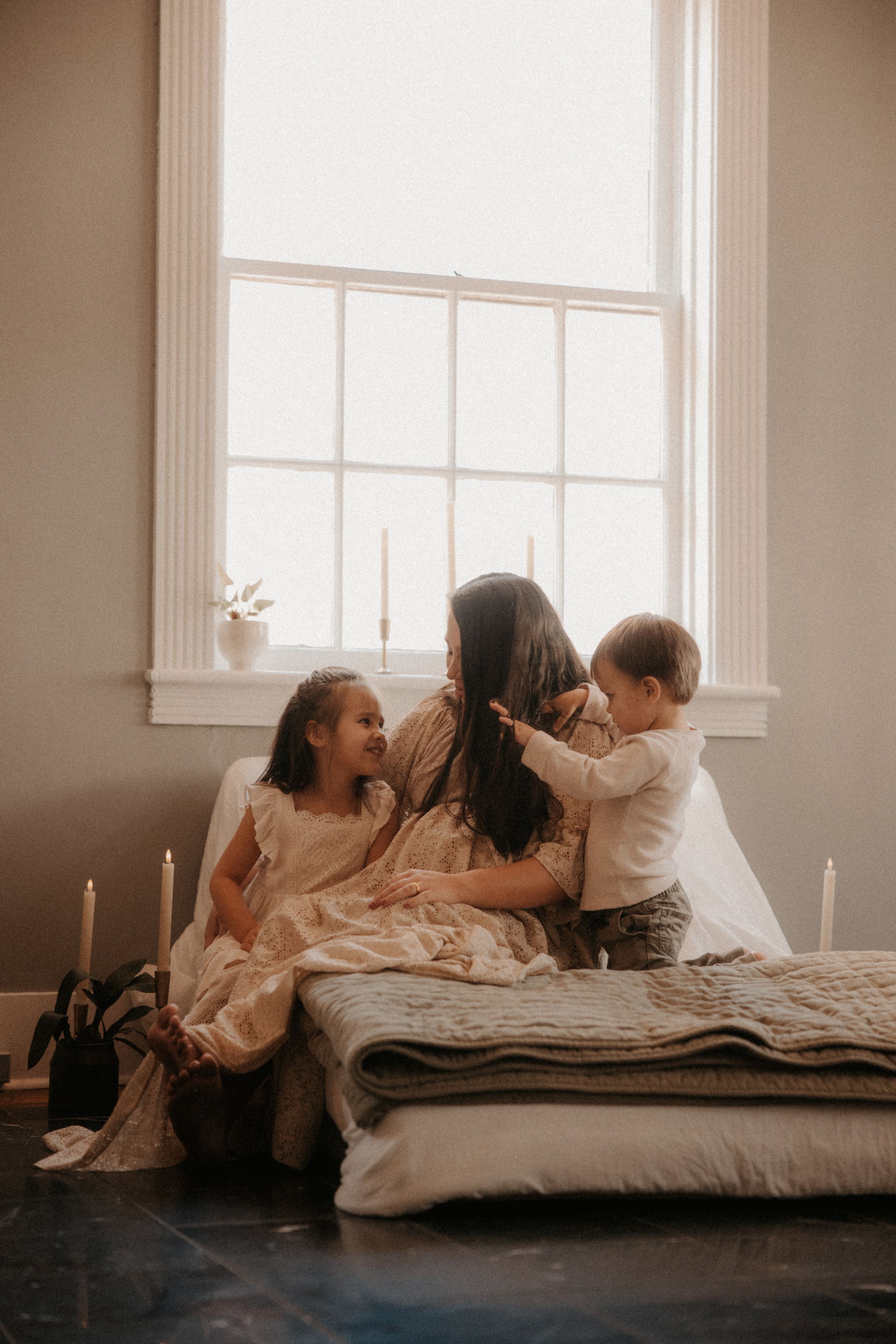 Three warm-toned photos show people relaxing together on a mattress in a sunlit room with white walls.