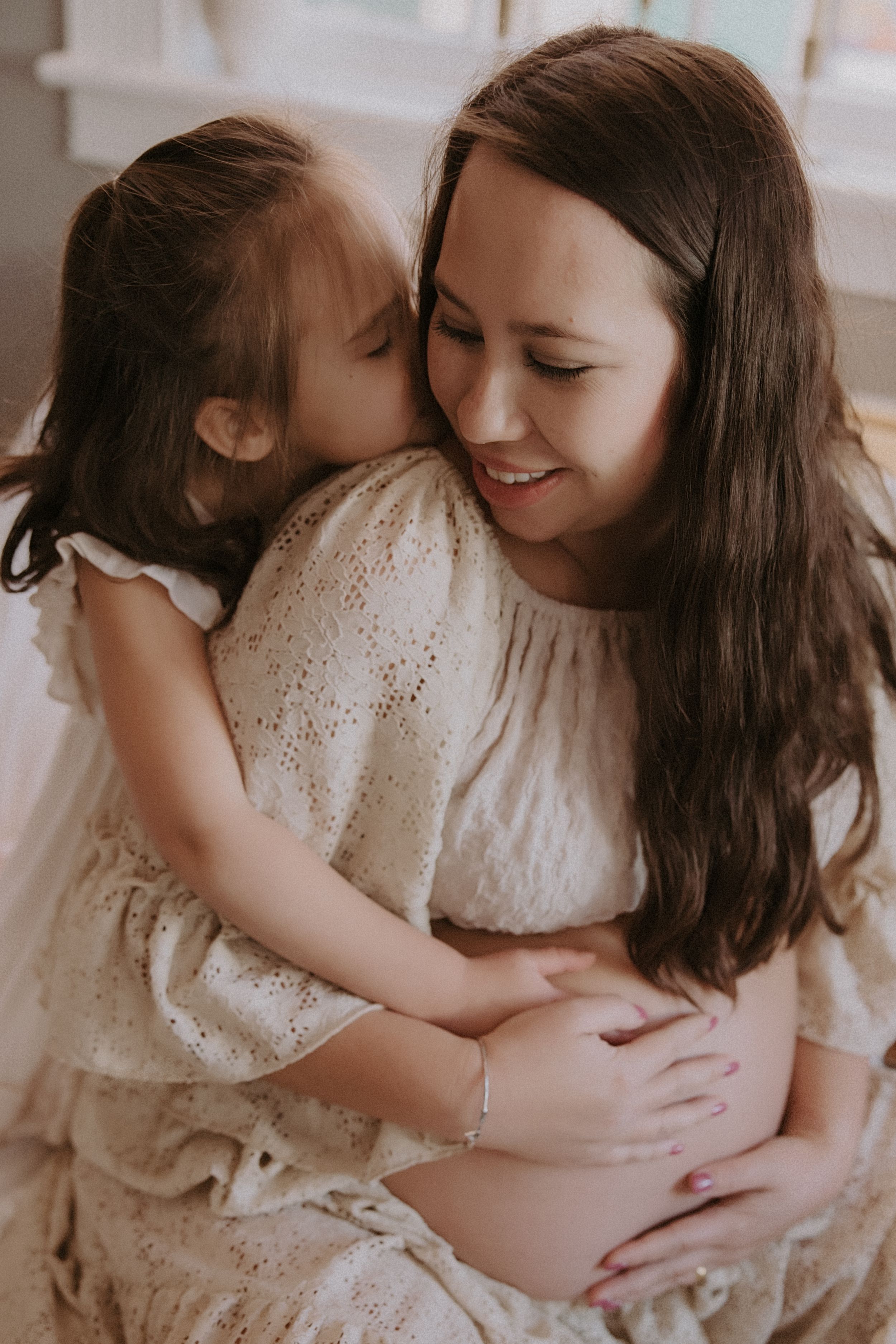 A tender moment between parent and child in soft sepia tones showing loving embrace and connection.