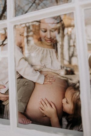 A tender moment captured through white railings as a parent and child share an intimate embrace.