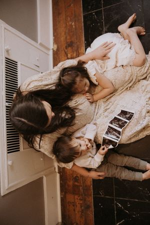 A sequence of photos showing someone lying on a wooden floor looking at ultrasound photos in a vintage-style setting.