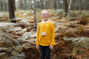 petite fille en pull jaune dans une forêt en automne lors d’une séance photo dans les Yvelines