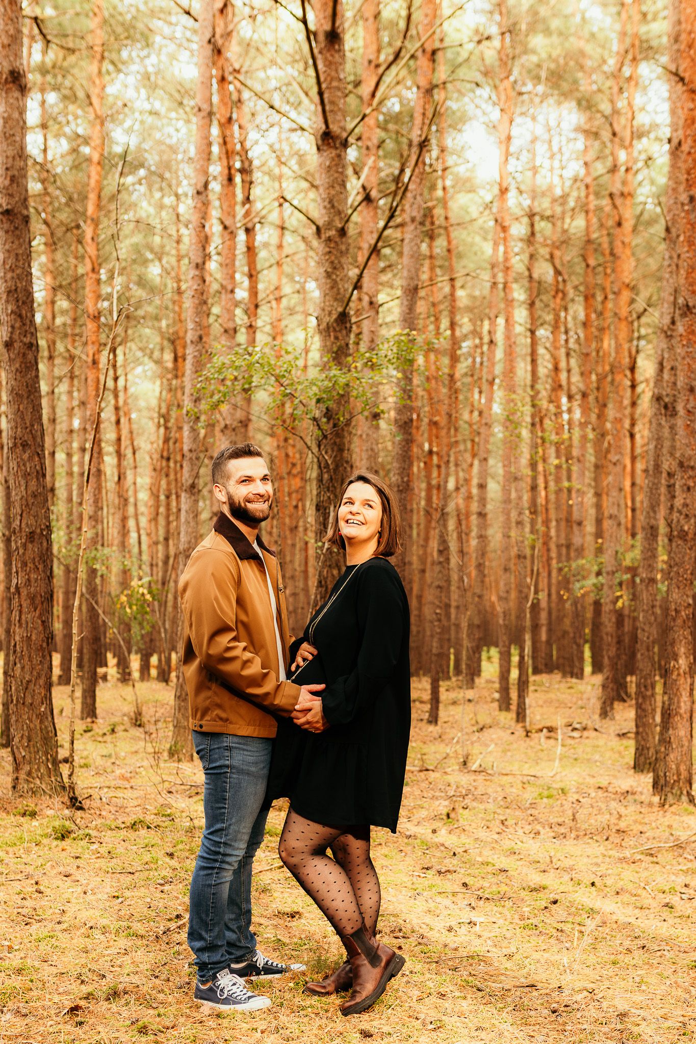 couple en forêt de pins en automne lors d’une séance photo dans les Yvelines avec une lumière dorée