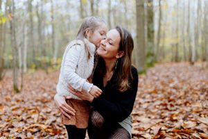 maman et sa fille assises dans les feuilles en forêt lors d’une séance photo en automne dans les Yvelines
