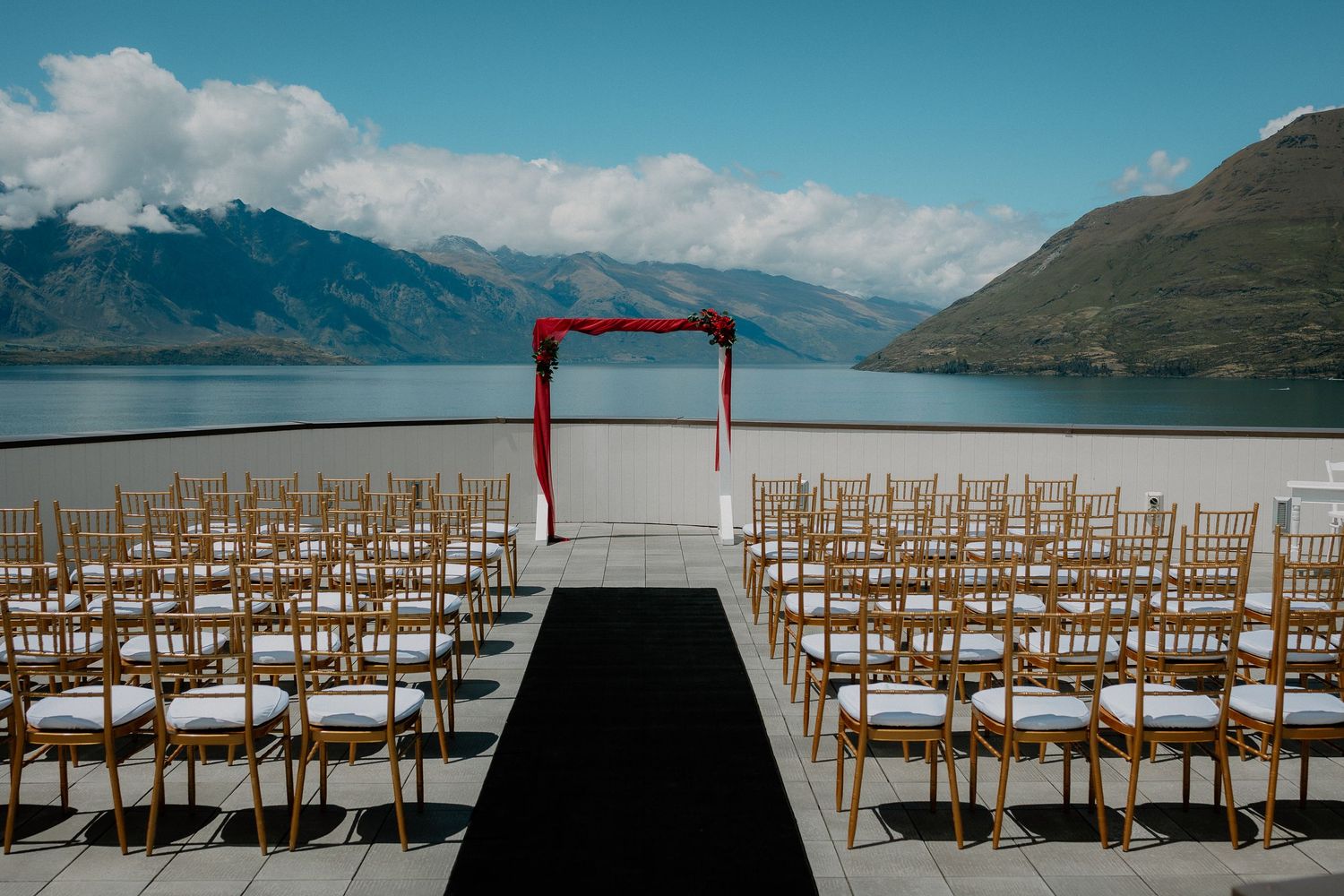 An outdoor wedding ceremony set up with mountain peaks and Lake Wakatipu in the background at Rendezvous Heritage Hotel, Queenstown, NZ.