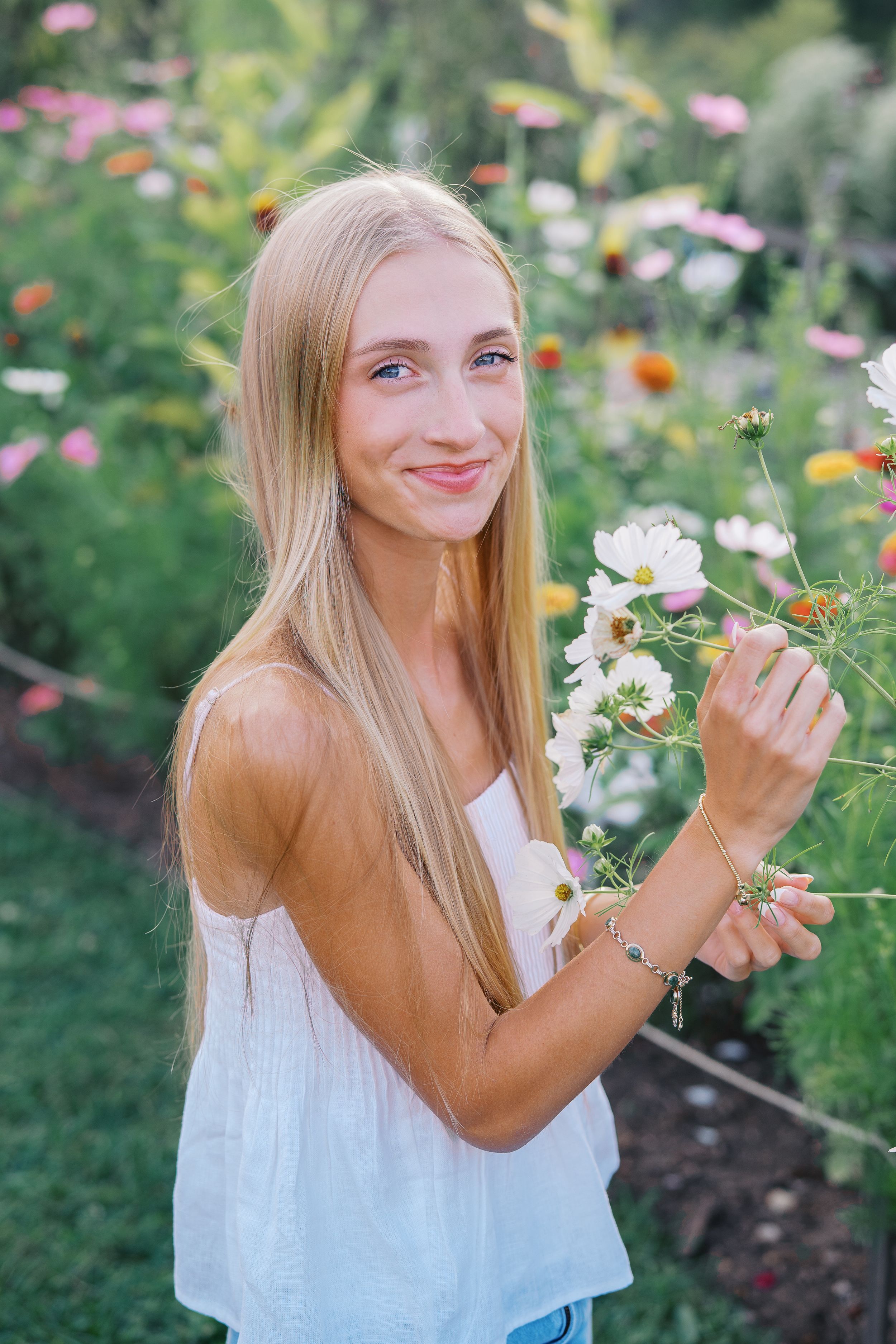 A summer portrait in a wildflower garden with colorful cosmos and daisies blooming in the background.