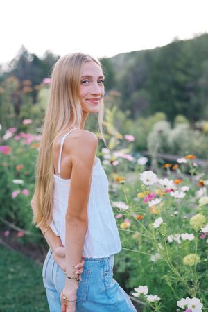 A candid moment captured in a flower field wearing a white top and denim on a sunny day.