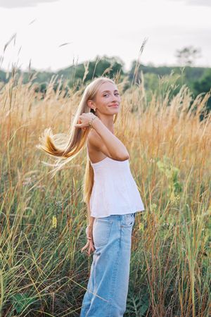 Playful outdoor portraits with flowing hair against a backdrop of tall grass at sunset.
