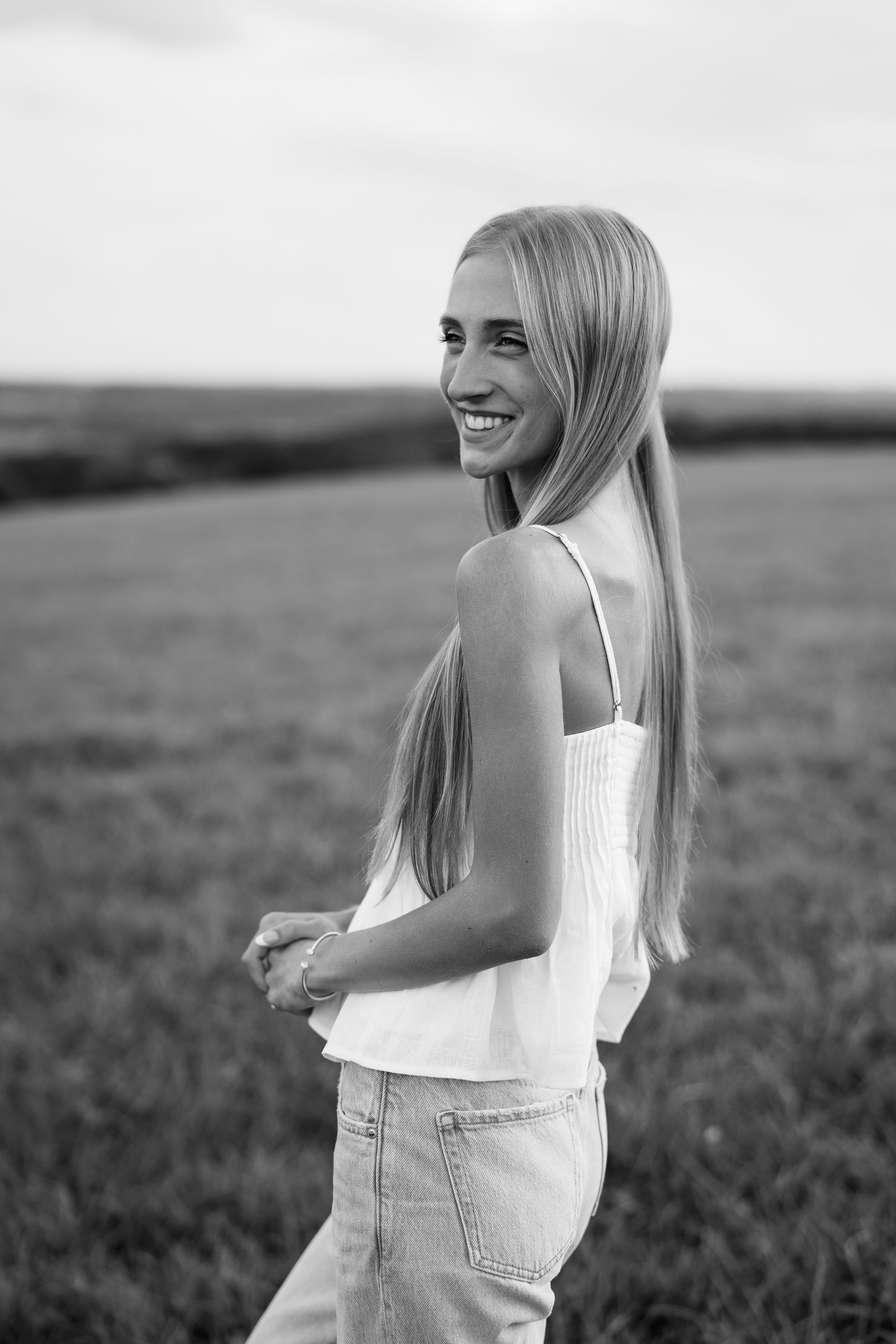 Black and white portrait of woman in casual outfit smiling over shoulder.
