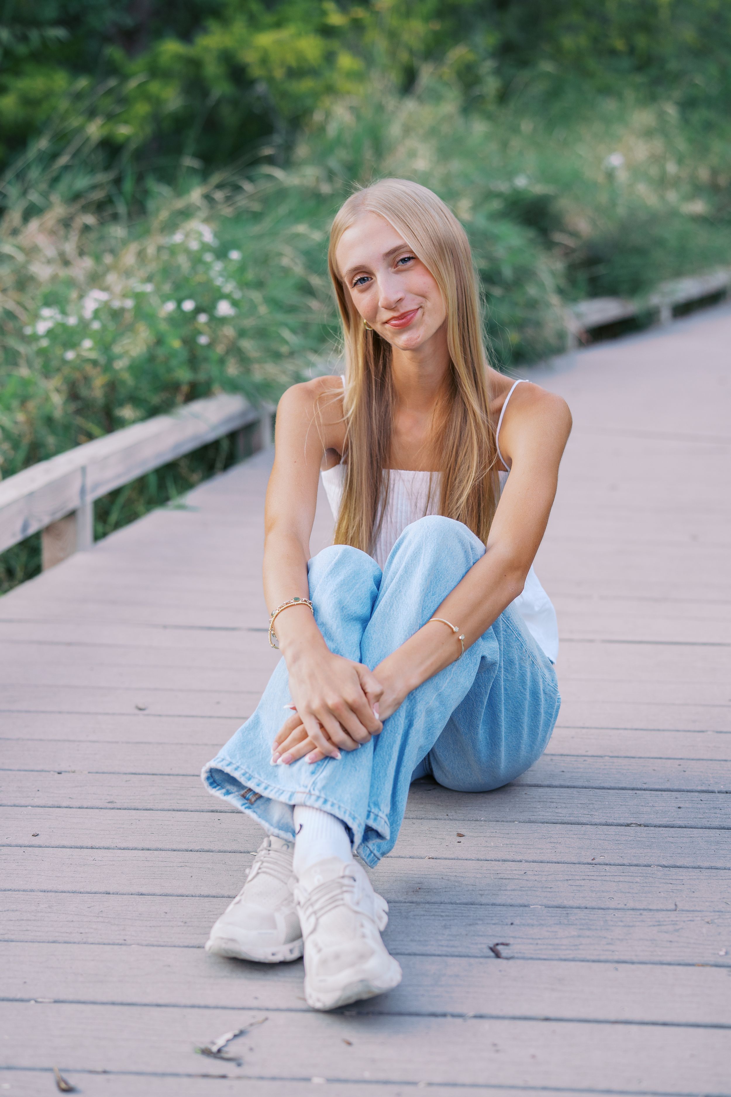 Someone relaxes on a wooden deck wearing casual summer clothing.