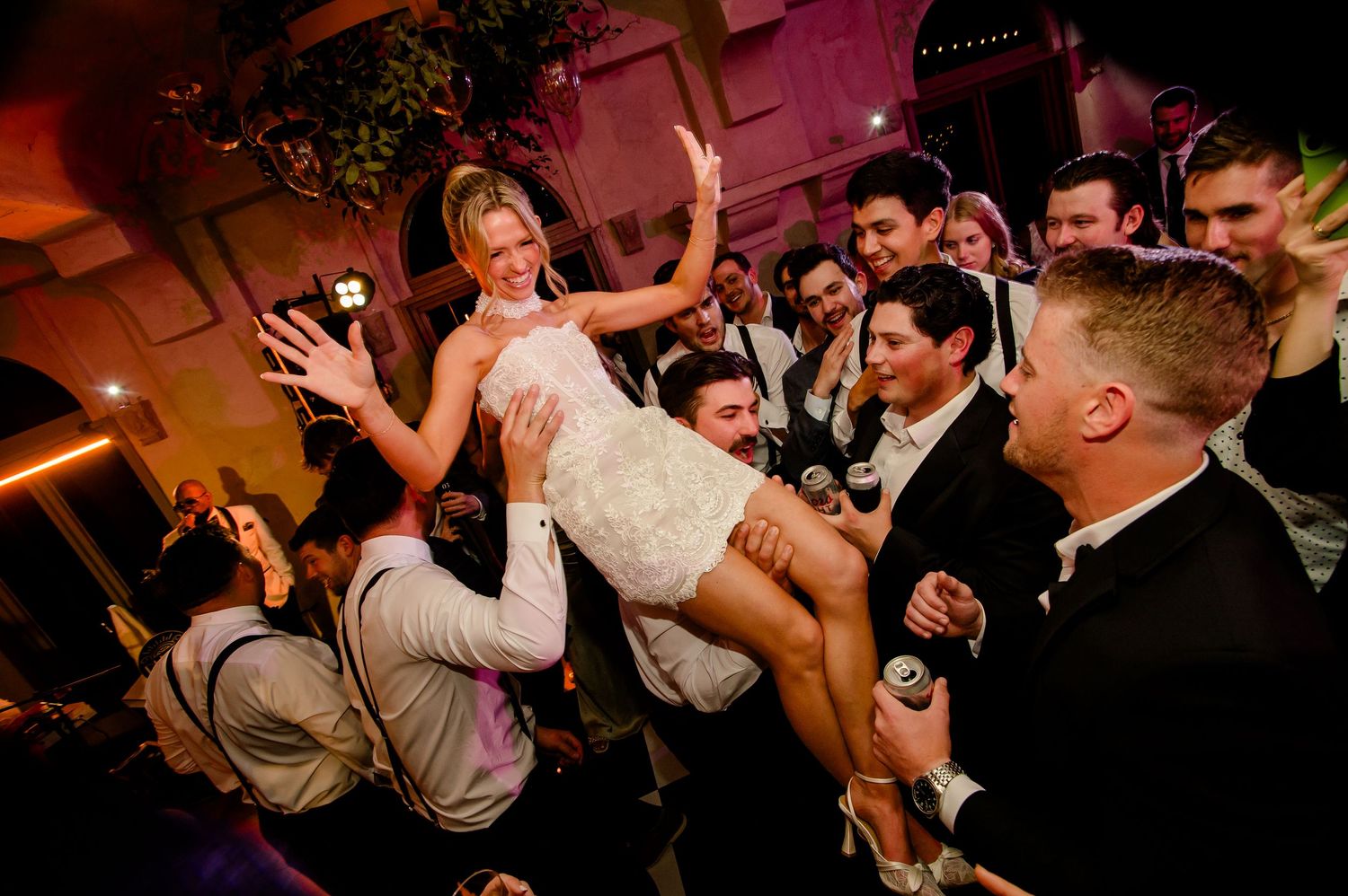 A lively wedding reception dance floor filled with guests celebrating and dancing under warm lighting.